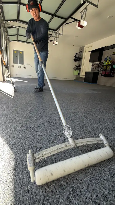 Altangerel Shoovdor rolling the polyaspartic top coat over the Nightfall flake floor in a McLean garage