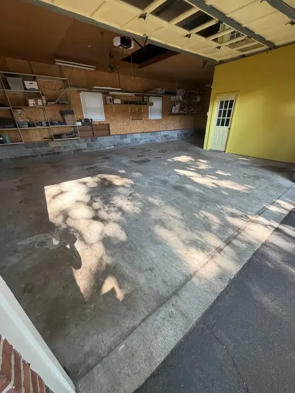 Bare, sun-dappled concrete in the Annandale garage before the flake coating was installed