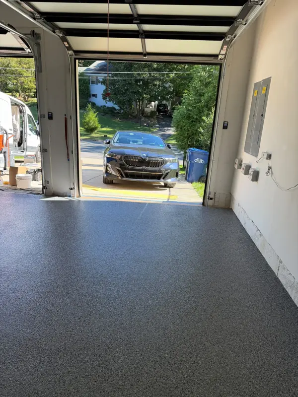 Nightfall flake floor in a McLean garage bay seen toward the open overhead door and driveway