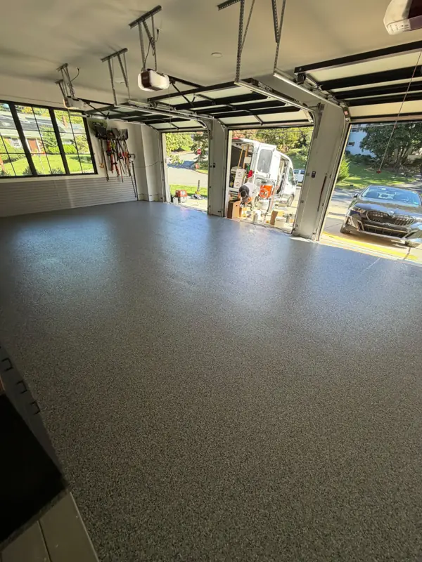 Wide view of a finished Nightfall flake floor across a McLean, VA three-car garage, looking toward the open doors