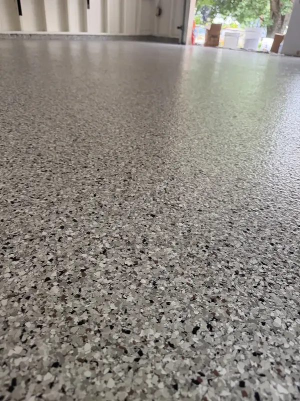 Low-angle close-up of the Coyote flake finish stretching toward the garage entrance in Potomac