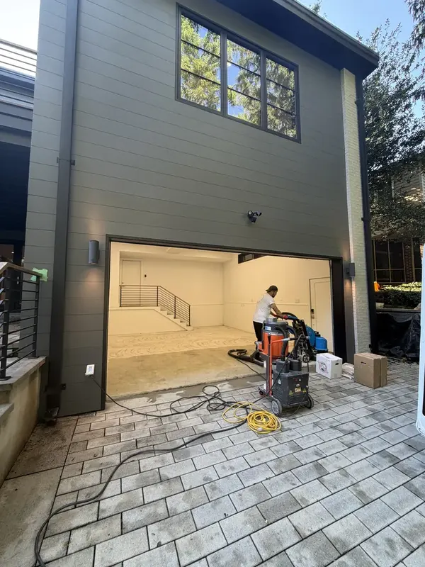 Open garage in Washington, DC during surface preparation, with grinding equipment on the paver driveway