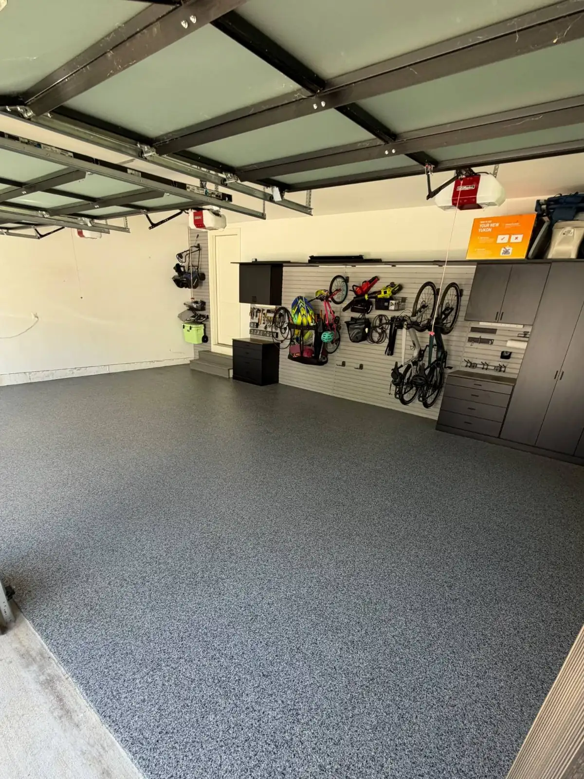 The same garage after coating: blue-grey full-flake floor in front of slatwall storage
