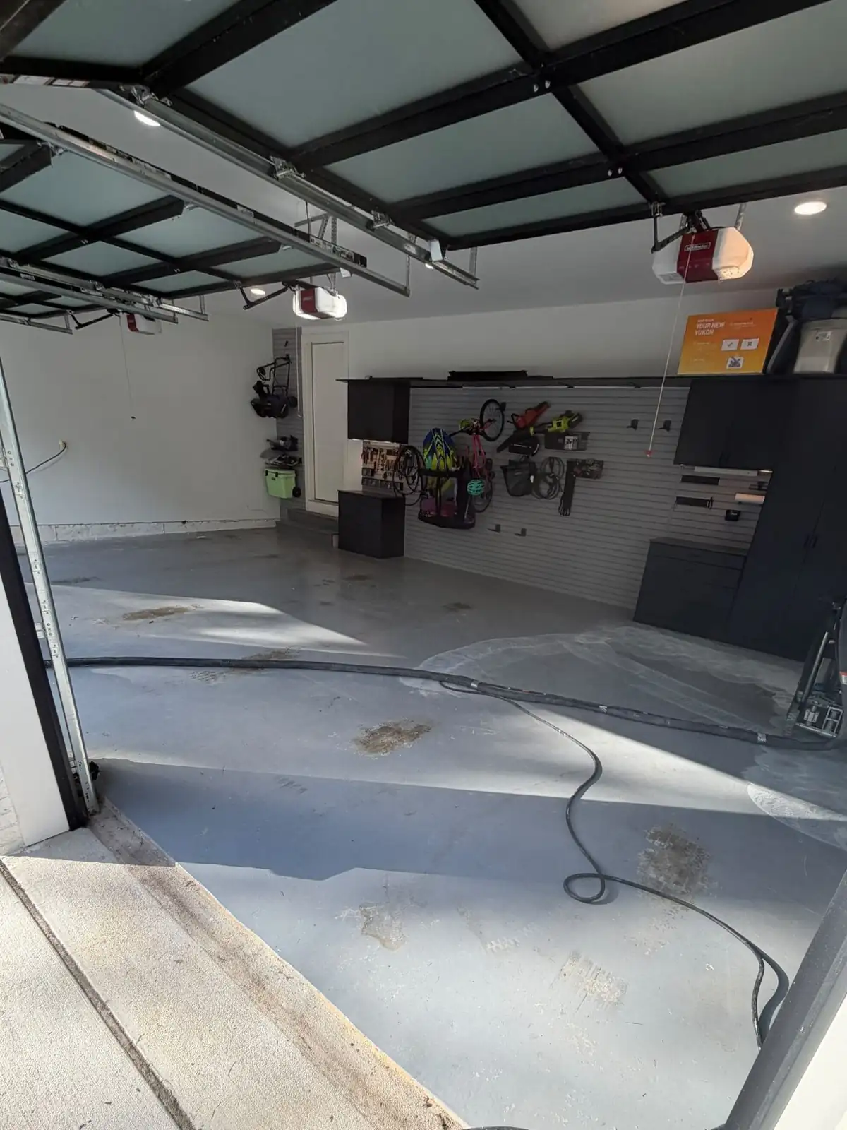 Garage floor before coating: worn grey concrete with stains, grinder hoses on the floor