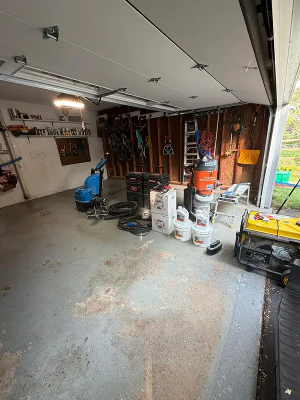 Herndon, VA garage before coating, with stained concrete and the crew's grinding equipment